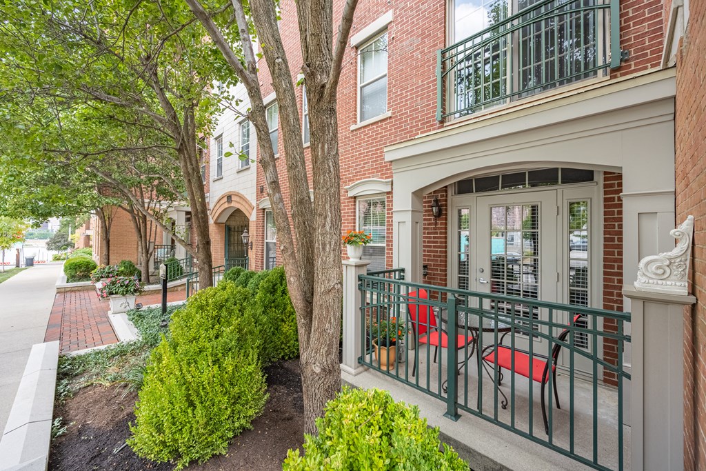 a patio with red chairs on a balcony in front of a brick building