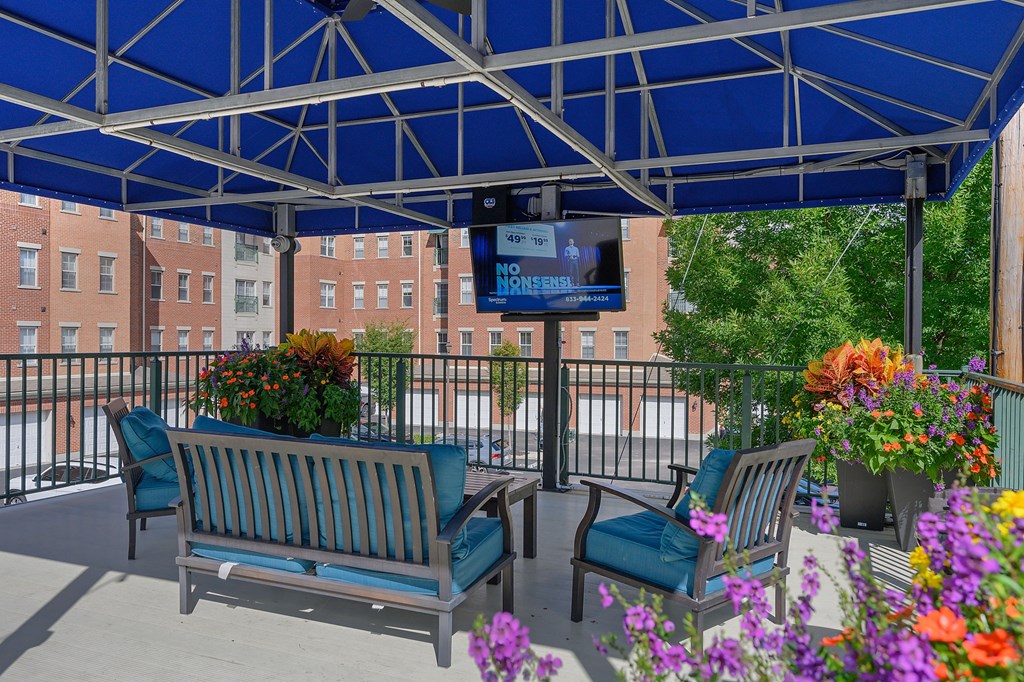 a covered patio with benches and flowers and a tv