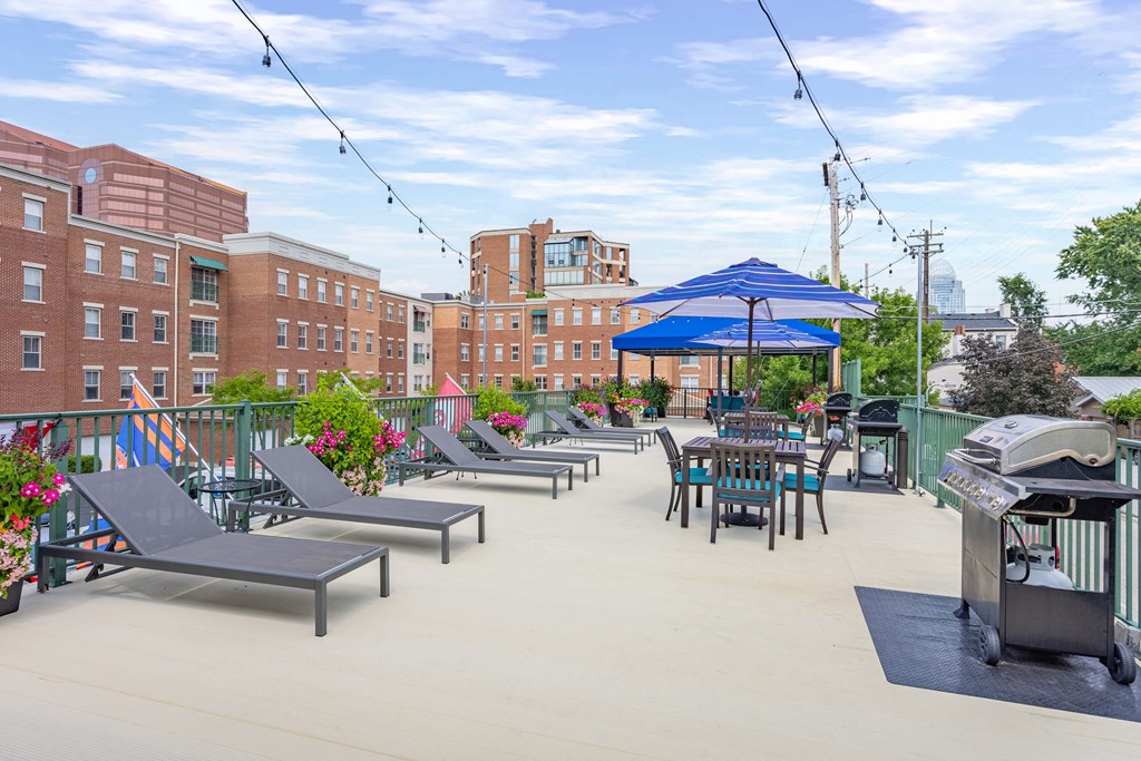 an outdoor patio with tables chairs and umbrellas and a grill