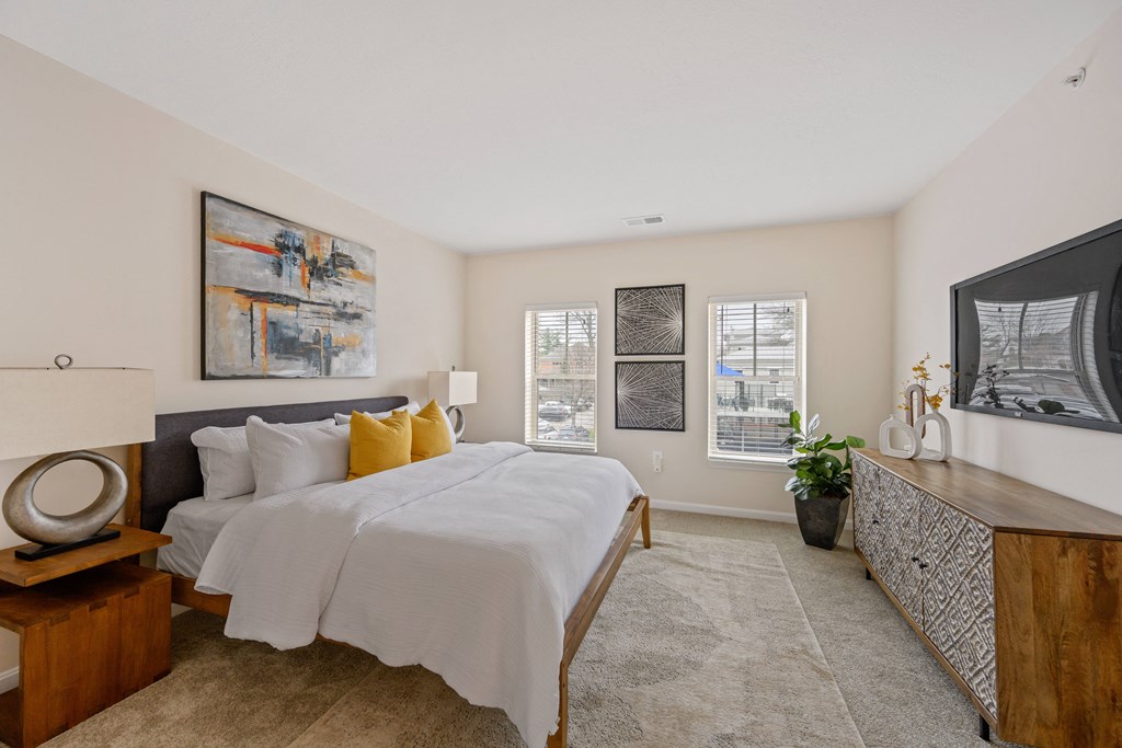 a bedroom with white bedding and yellow pillows