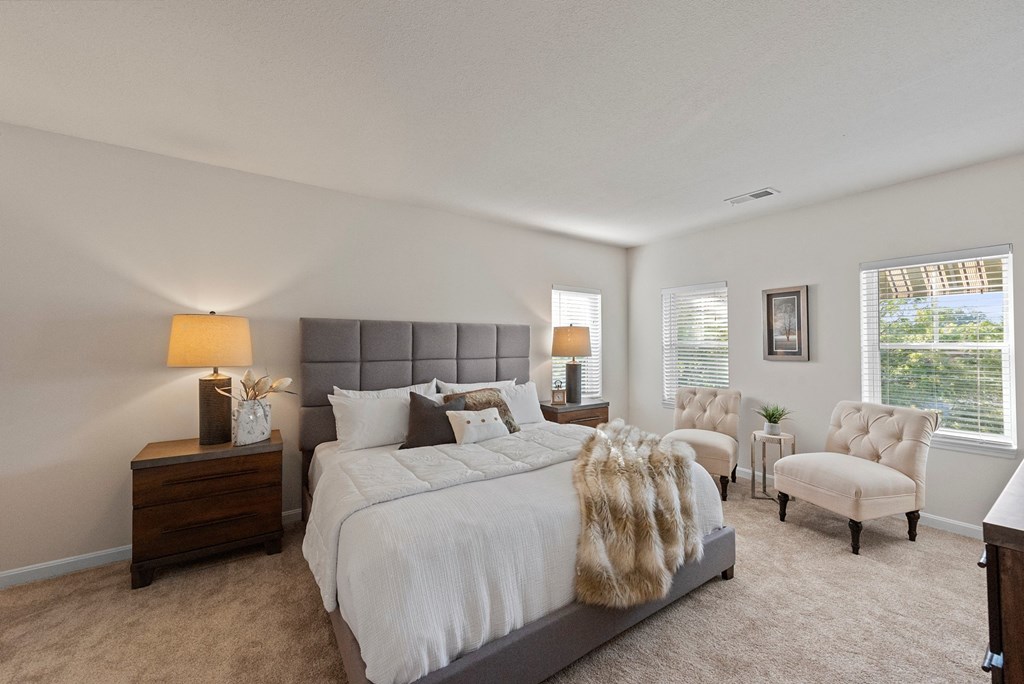 a bedroom with a bed and a chair and a window