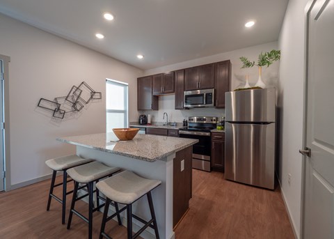 a kitchen with stainless steel appliances and a counter with three stools
