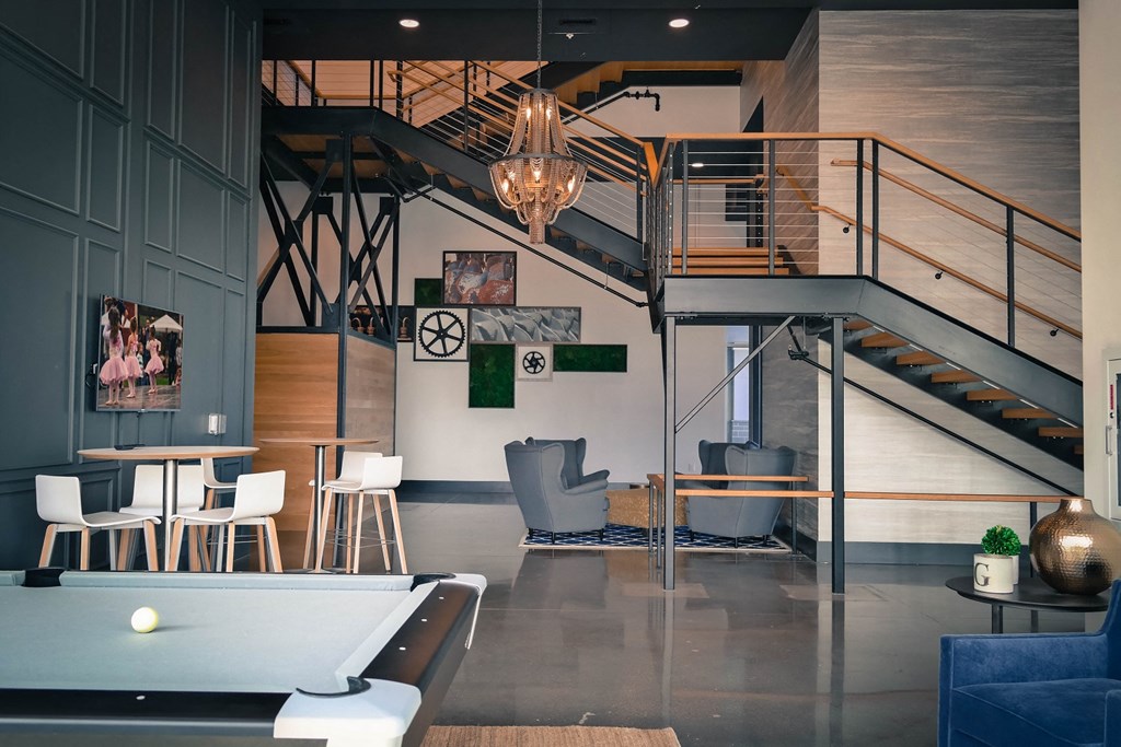 a living room with a pool table and stairs