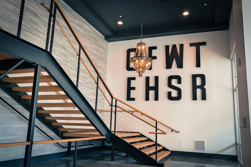 a staircase with a chandelier in front of a wall with a large sign