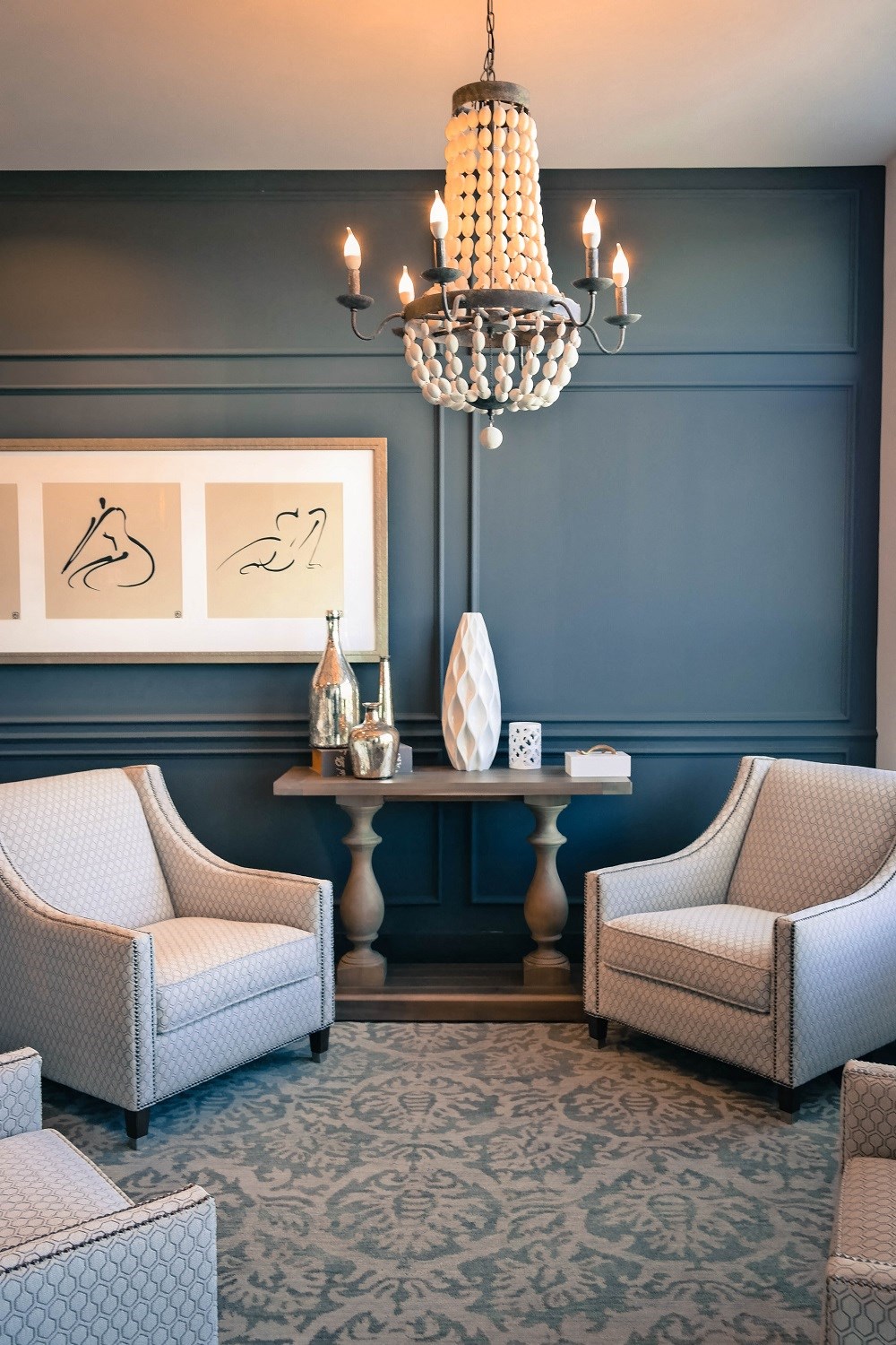 a living room with blue walls and chairs and a chandelier