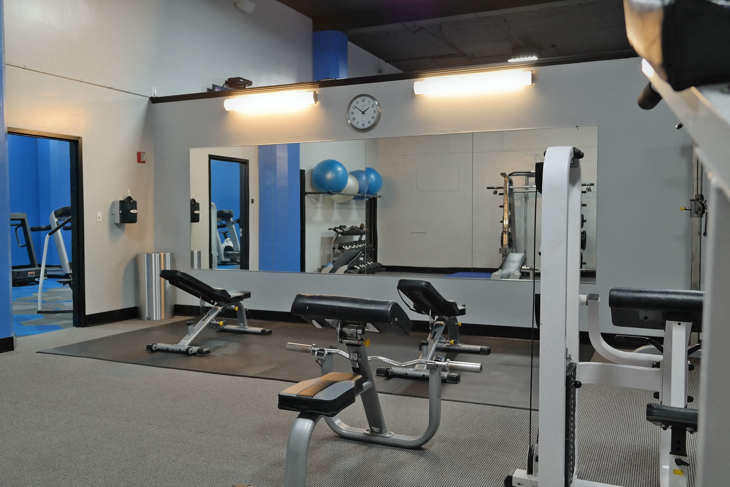 a gym with exercise equipment and a clock on the wall