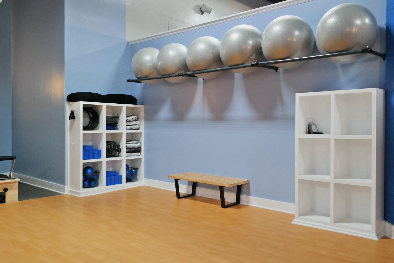 a yoga room with a bench and balls on the wall and a shelf with spheres
