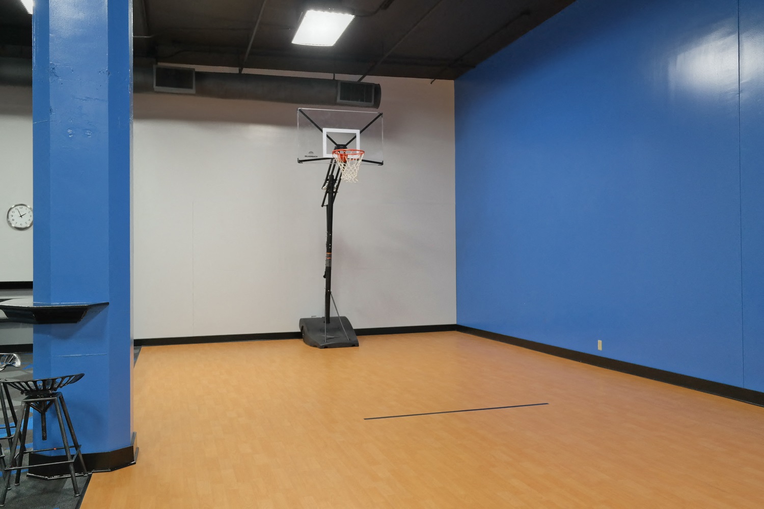 a basketball hoop in a room with blue walls and a wooden floor