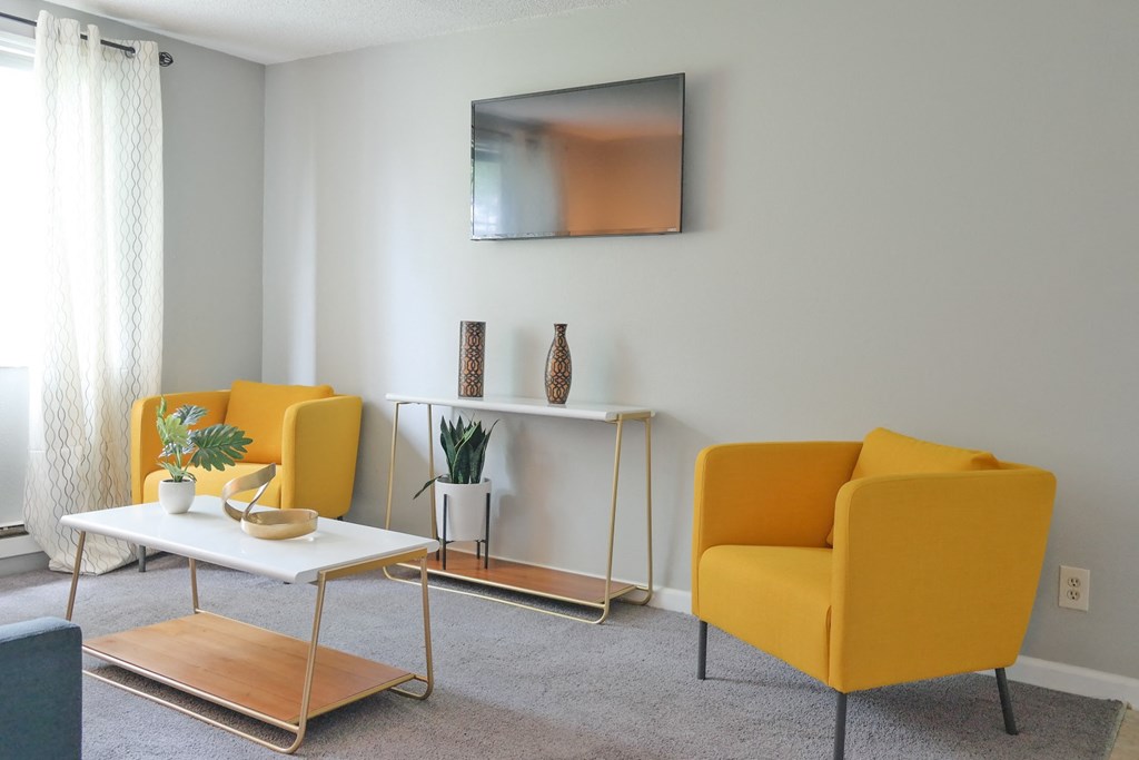 a living room with yellow chairs and a table and a television