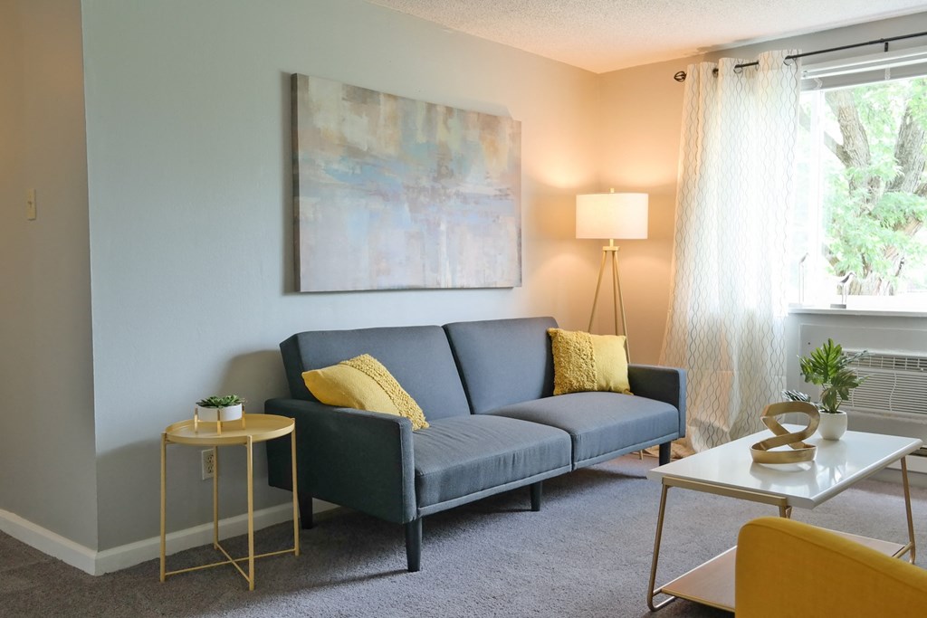 a living room with a blue couch and a painting on the wall
