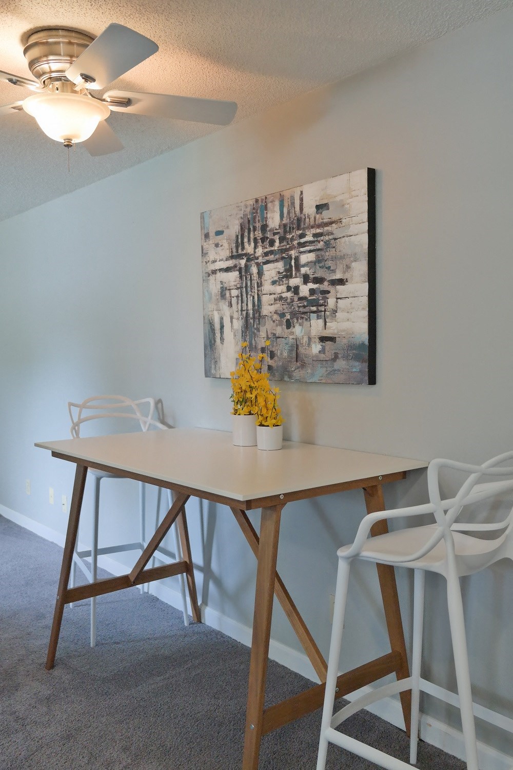 a dining area with a table and chairs and a painting on the wall
