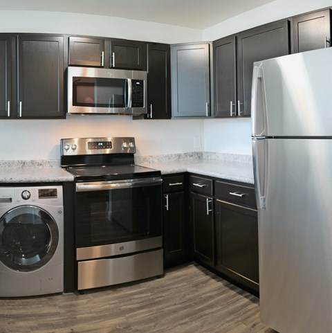 a kitchen with black cabinets and stainless steel appliances and a refrigerator