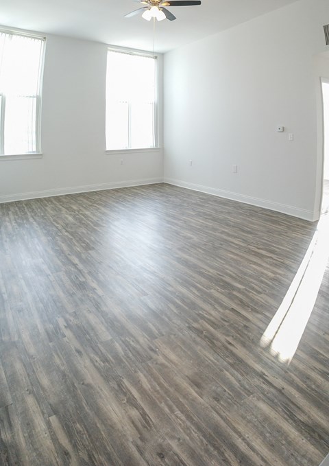 an empty living room with wood floors and a ceiling fan