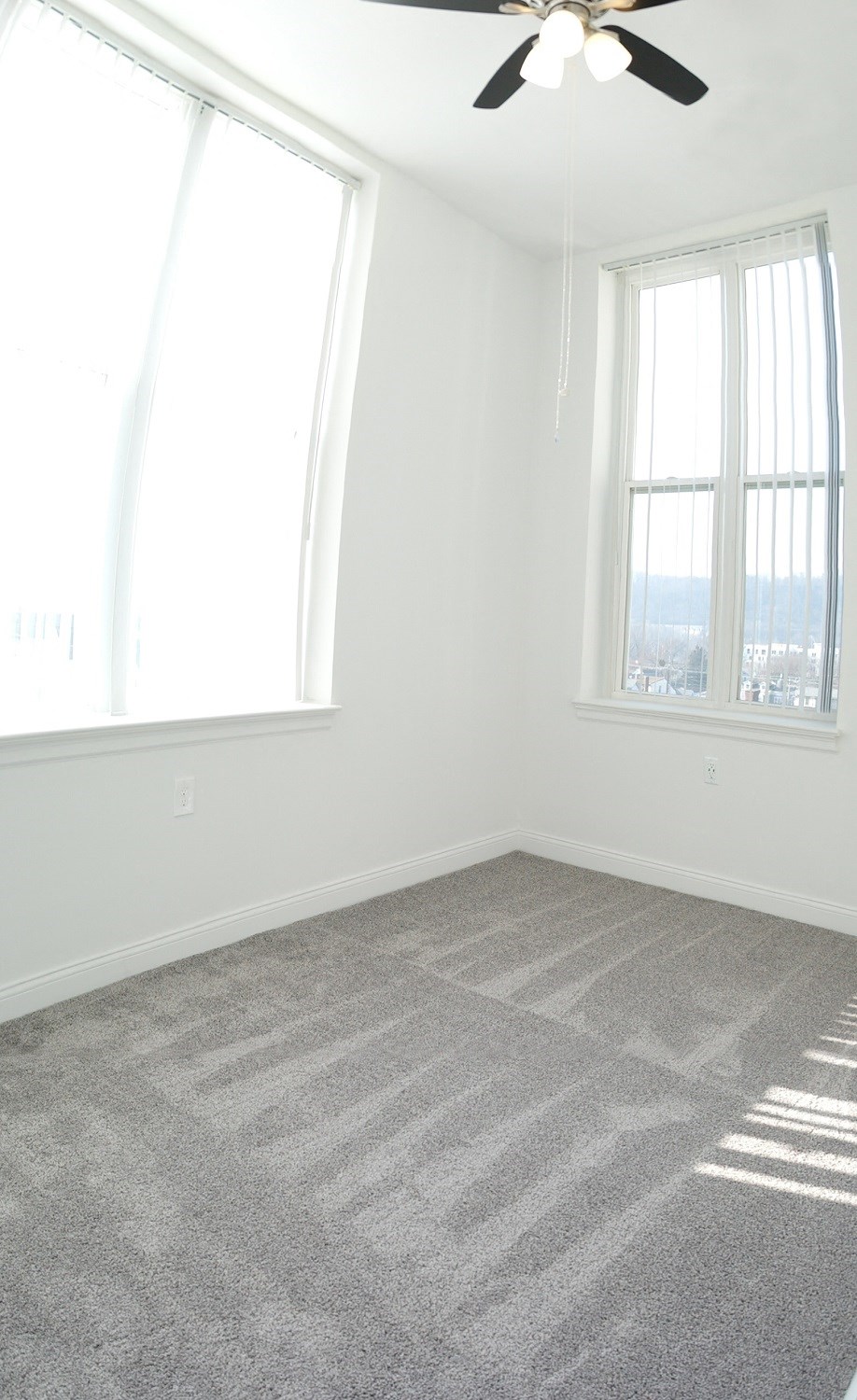 an empty room with carpet and two windows