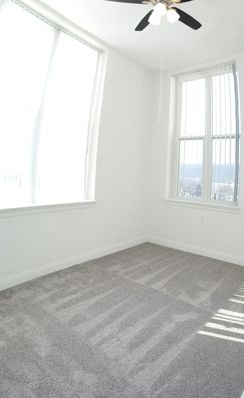 an empty room with carpet and two windows