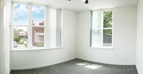 an empty room with three windows and a carpeted floor