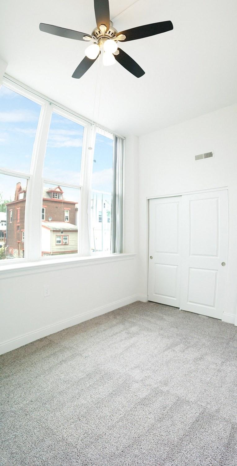 an empty room with a large window and a ceiling fan