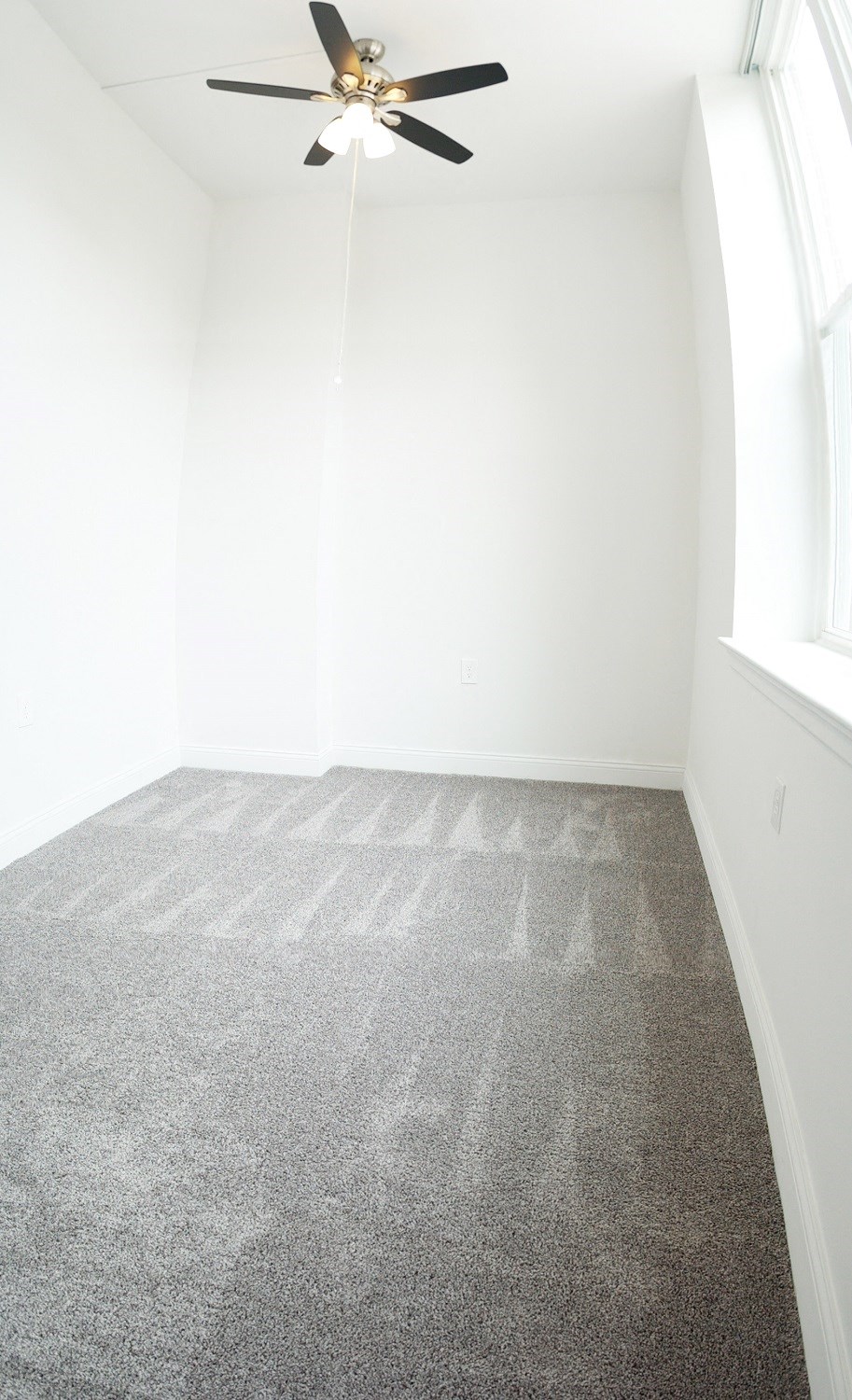 an empty room with carpet and a ceiling fan