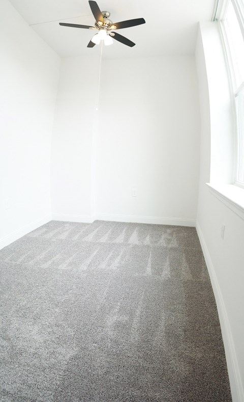 an empty room with carpet and a ceiling fan