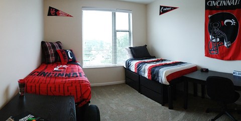 a bedroom with two beds and a desk and a window