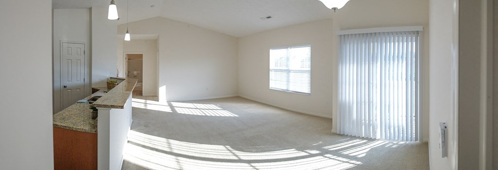 an empty living room with a large window and blinds