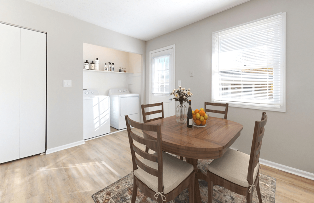 a dining room with a wooden table and chairs and a kitchen with a washing machine at Stonebrook of Franklin, Franklin, 46131