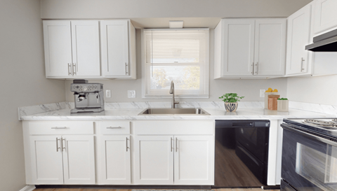 a white kitchen with white cabinets and black appliances and a window at Stonebrook of Franklin, Franklin, IN, 46131
