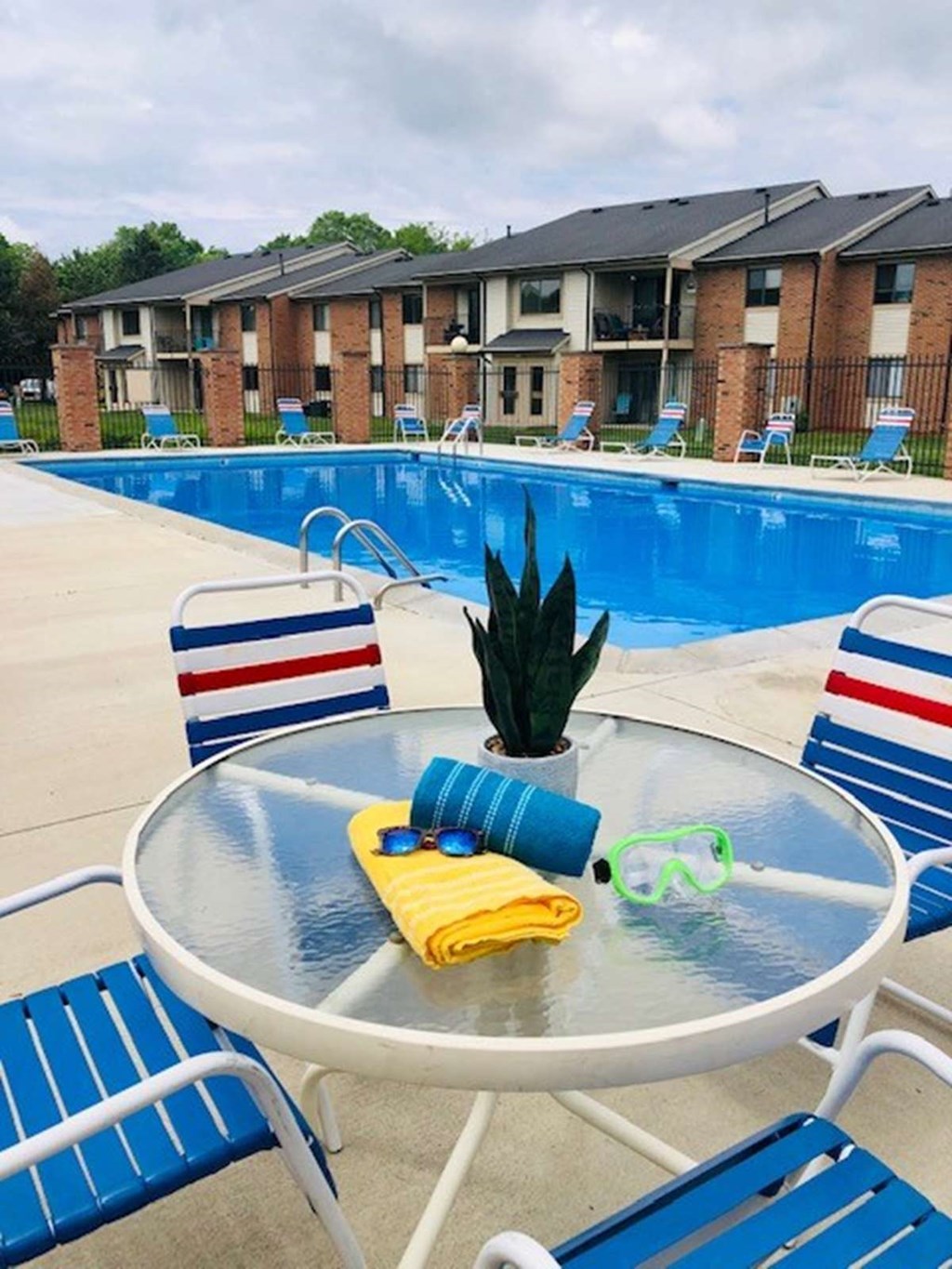 our apartments have a pool and a patio with chairs and a table