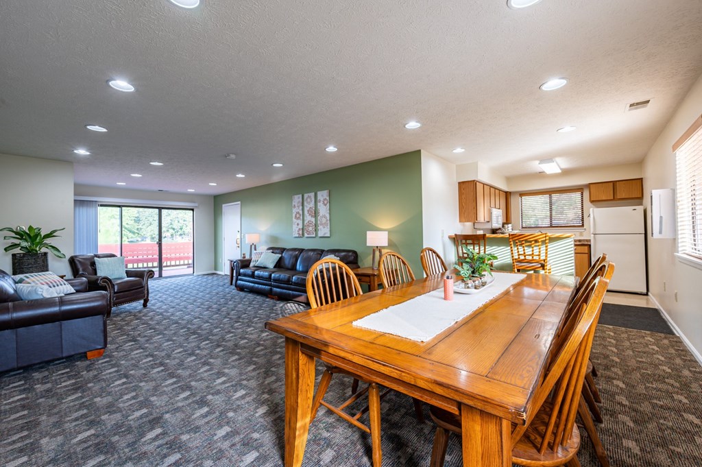 a living room with a wooden table and a kitchen