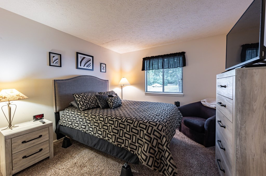 a bedroom with a bed and a dresser and a window