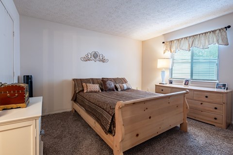 a bedroom with a bed and dresser and a window