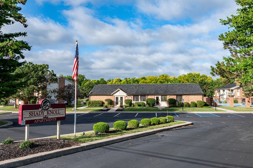 an empty parking lot in front of a house with an flag