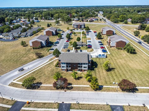 A large building is surrounded by a parking lot and a grassy area.