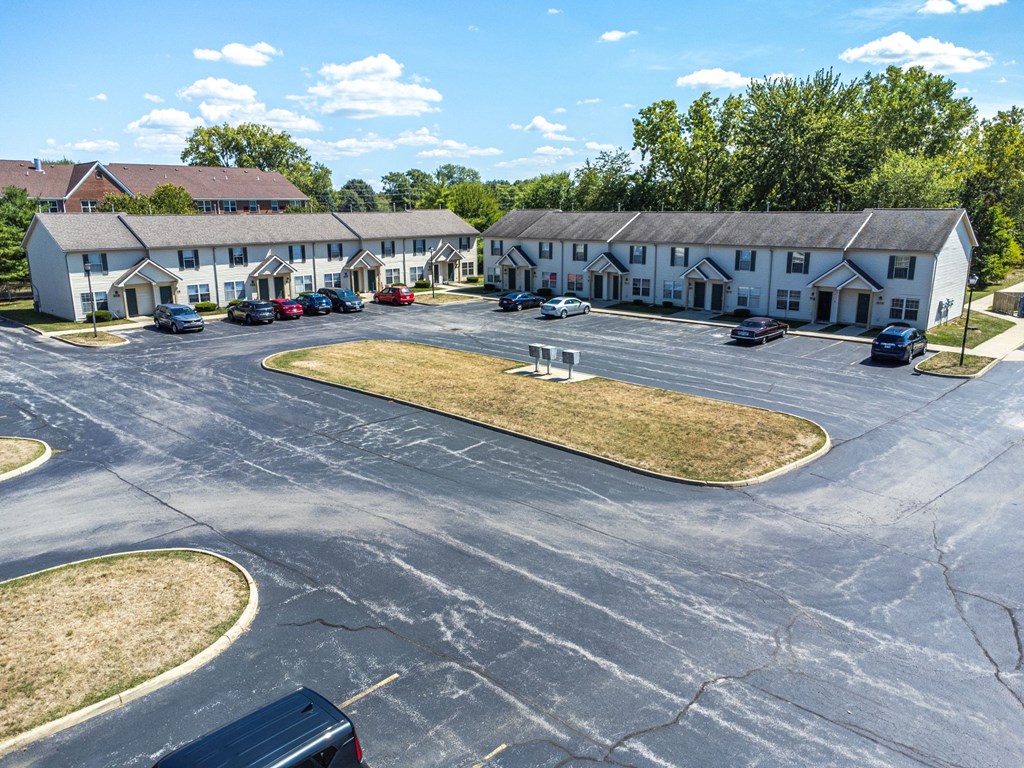 A parking lot with a few cars and a building in the background.