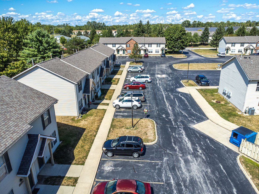 A parking lot in front of a building with cars parked.