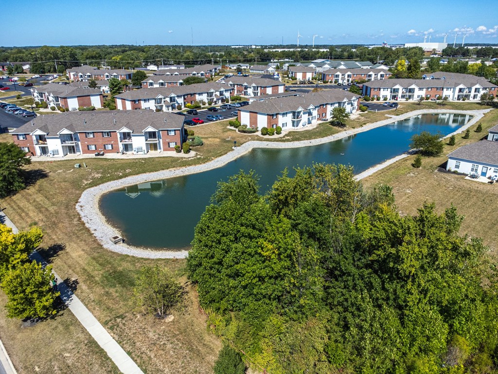 A bird's eye view of a residential area with a pond and trees.