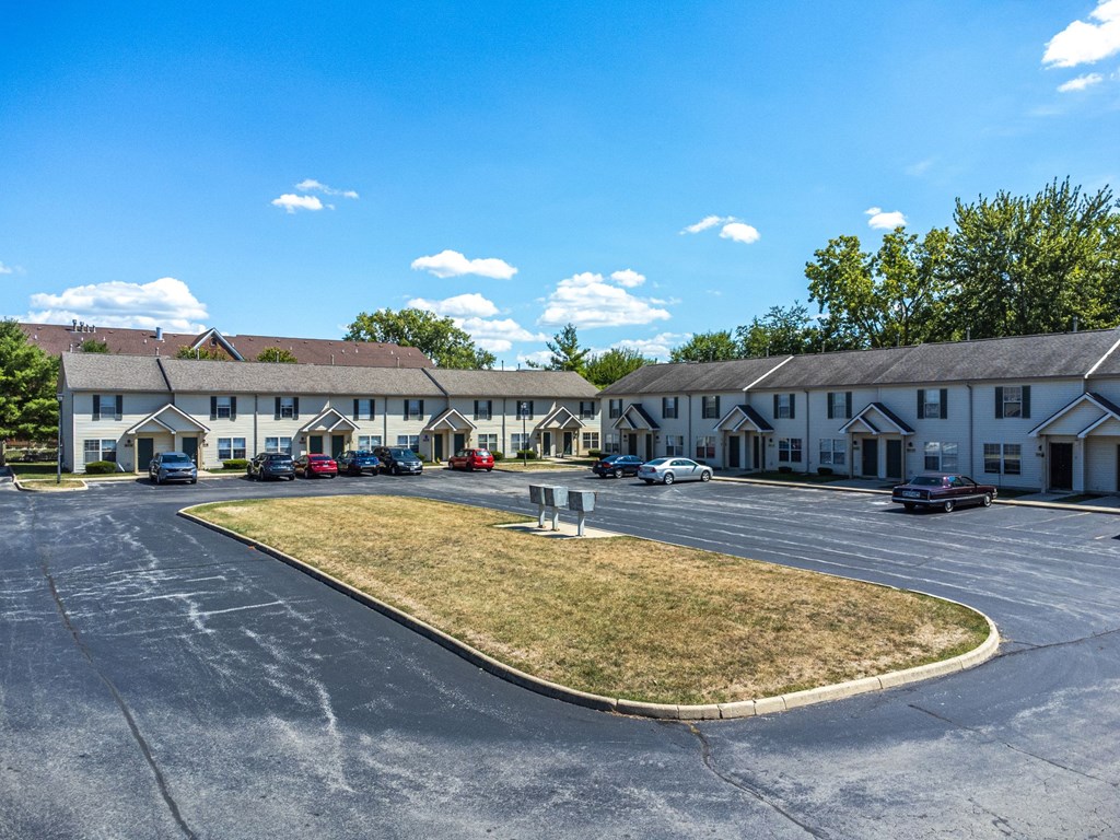 A parking lot in front of a building with cars parked.