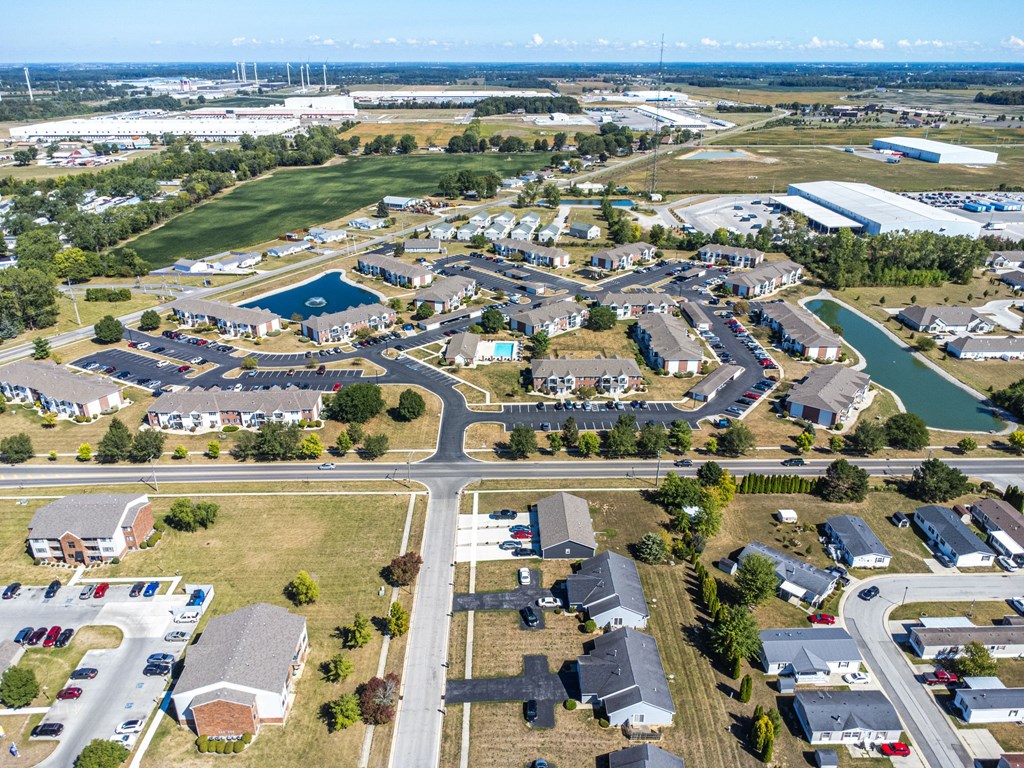 A bird's eye view of a residential area with houses, roads, and a swimming pool.