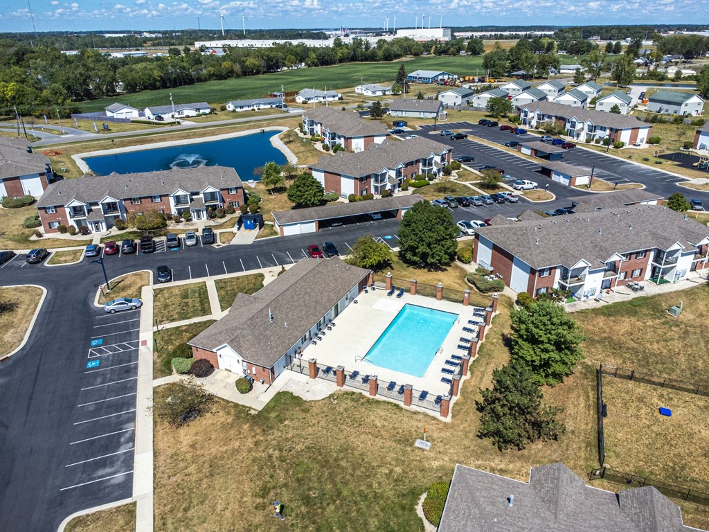 A bird's eye view of a residential area with houses, swimming pools, and a parking lot.