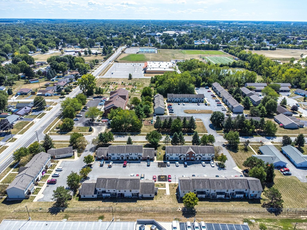 A bird's eye view of a residential area with houses, a school, and a parking lot.