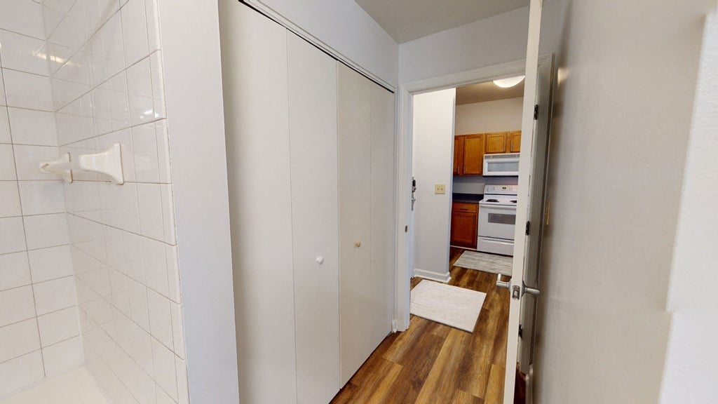 a bathroom closet and a doorway leading to a kitchen