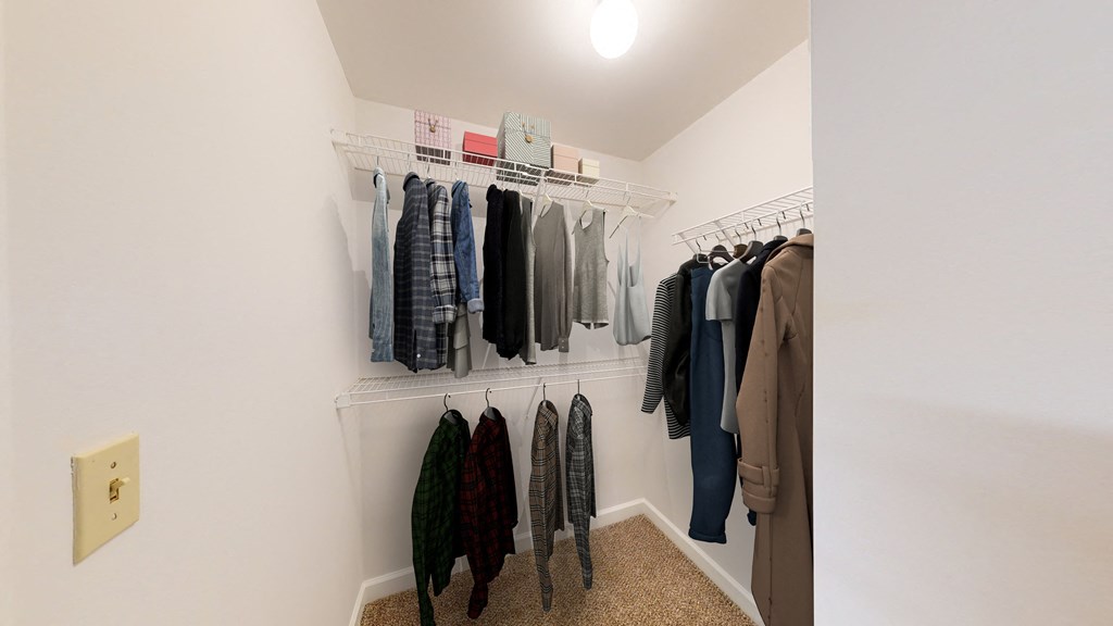 a walk in closet in a bedroom with white walls and a ceiling with a light