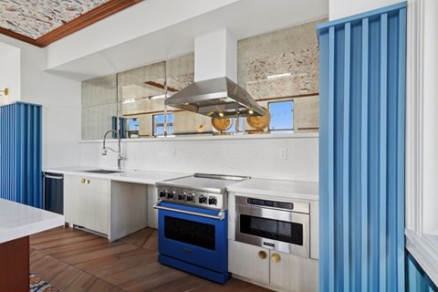A modern kitchen with a blue oven and white cabinets.