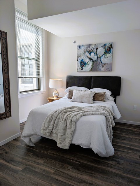 A bedroom with a large bed and a painting on the wall.