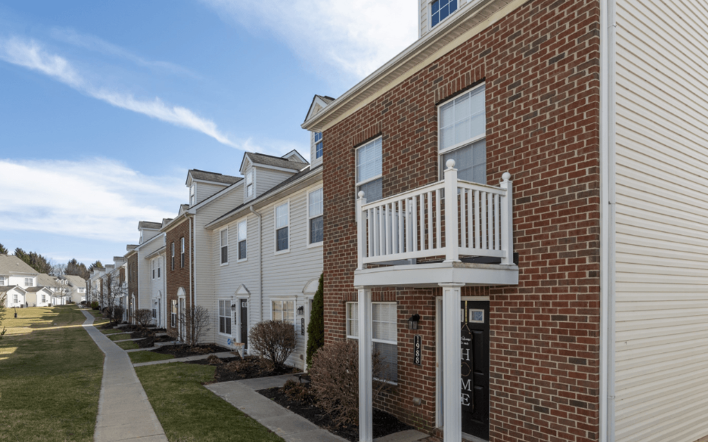 a row of brick apartments with a balcony and a sidewalk at Traditions at Slate Ridge, Reynoldsburg, OH 43068