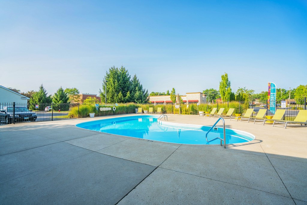 a swimming pool with yellow chairs around it and a blue sky