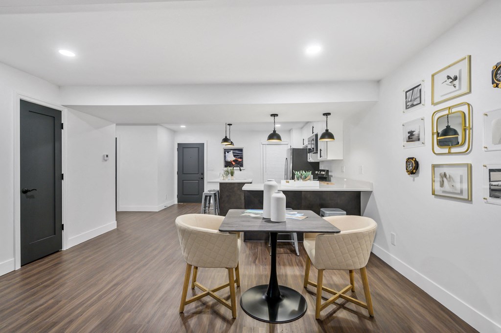 a dining area with a table and chairs and a kitchen in the background