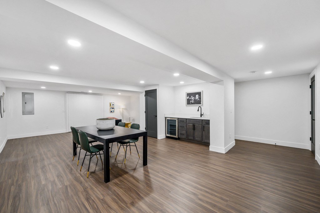 a dining area with a table and chairs and a kitchen in the background