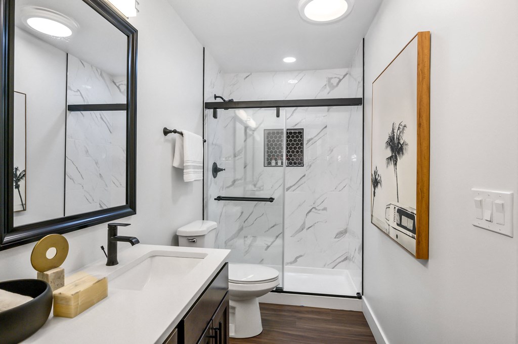 a bathroom with a toilet sink and shower with a glass door