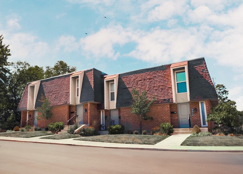 a brick house with a sidewalk in front of it
